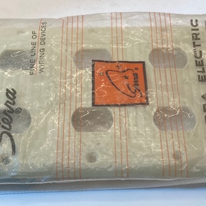 May include: A package containing two off-white Sierra Electric outlet covers. The covers have four outlet holes and are packaged in a clear plastic bag. The Sierra Electric logo is visible on the package.
