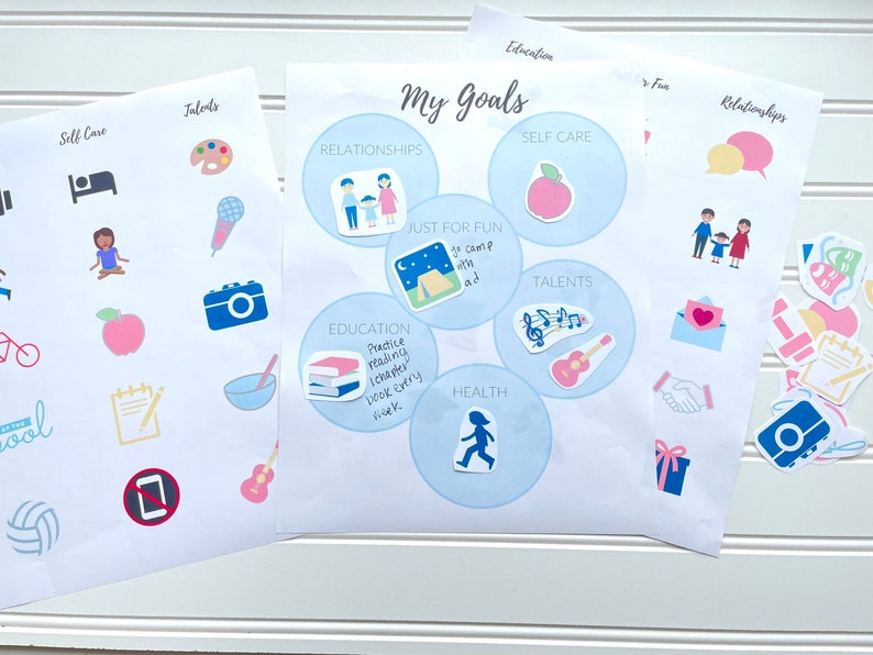K&ouml;nnte beinhalten: Zwei Bl&auml;tter Papier mit Grafiken zur Zielsetzung. Ein Blatt zeigt den Titel "Meine Ziele" mit Kategorien wie Beziehungen, Selbstpflege und Bildung. Das andere Blatt hat Symbole f&uuml;r Talente und Selbstpflege. Es gibt auch lose Aufkleber.