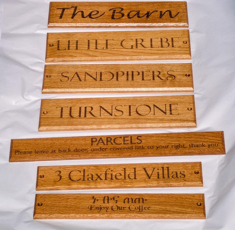 May include: A collection of seven rectangular wooden signs with engraved text. The signs feature various inscriptions including The Barn, LITTLE GREBE, SANDPIPERS, TURNSTONE, PARCELS, 3 Claxfield Villas, and Enjoy Our Coffee, with some including mounting holes.