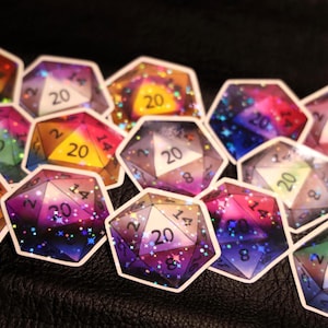 以下が含まれることがあります： カラフルな銀河をテーマにしたD20サイコロステッカーのコレクション。各ステッカーは異なる配色で、数字と20が目立つように表示されています。テーブルトップゲーム愛好家向けです。