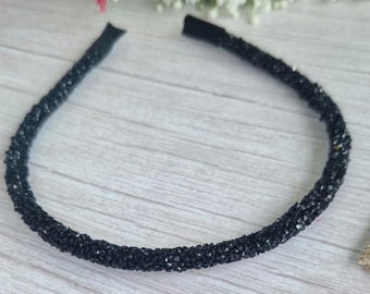 Puede incluir: Una diadema negra con pequeños diamantes de imitación negros. La diadema es flexible y tiene un diseño sencillo.