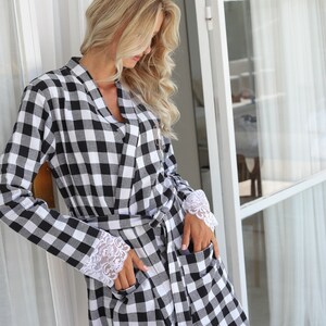 May include: A black and white checkered robe with white lace trim on the cuffs. The robe has a sash tie and pockets.