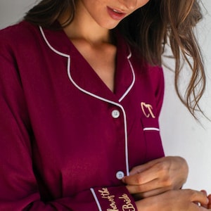 May include: Burgundy pajama top with white piping and gold embroidery that reads "Mother of the Bride".