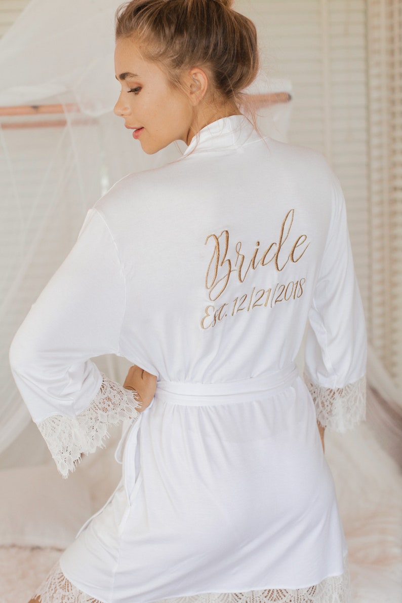 May include: White satin robe with lace trim and the words "Bride Est. 12/21/2018" embroidered on the back.