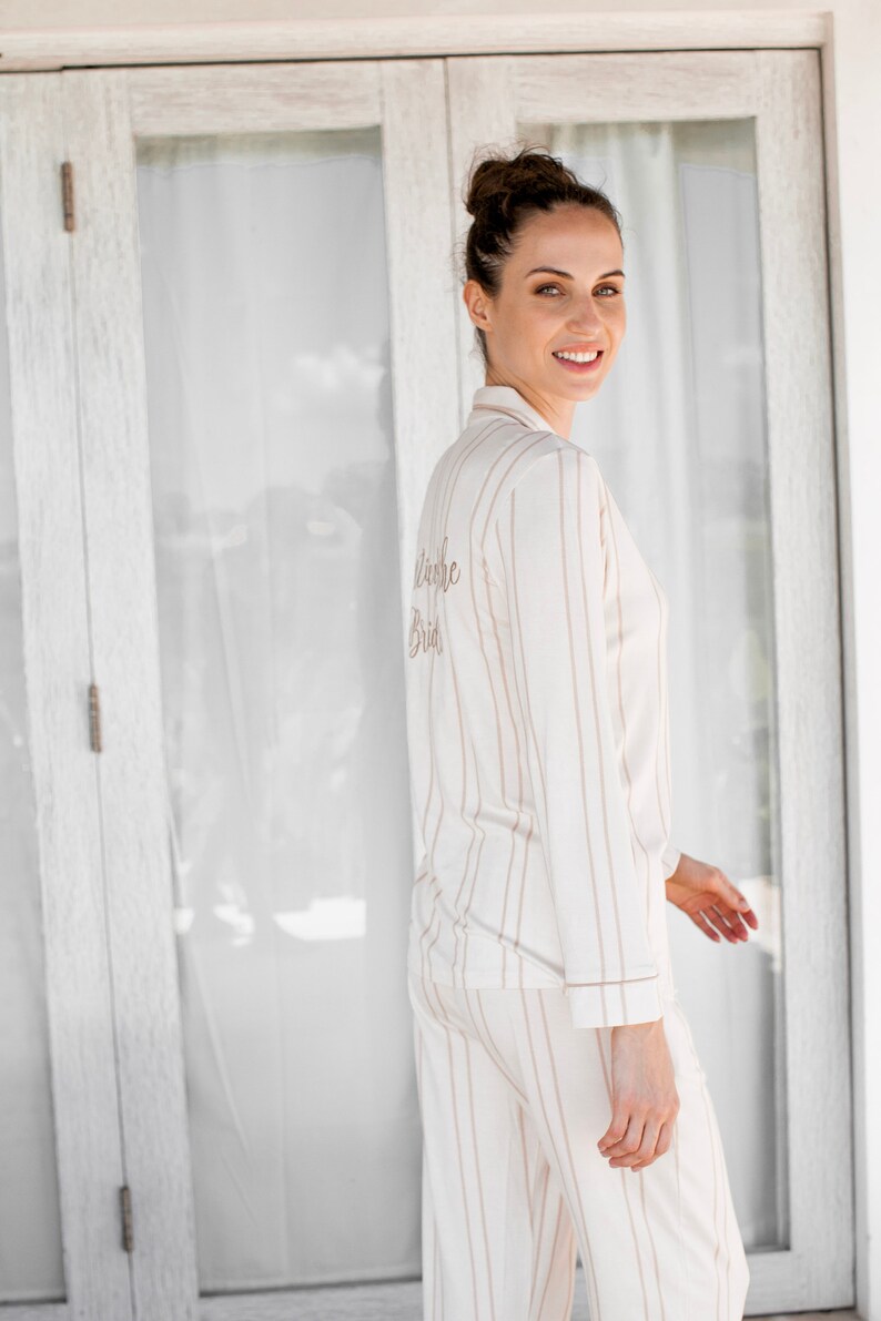 Puede incluir: Una mujer con un pijama a rayas blancas y marrones con el texto "Future Bride" bordado en la espalda.