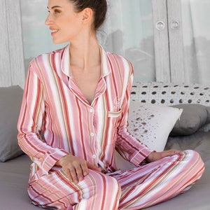 May include: A pink and white striped pajama set with long sleeves and pants. The pajamas have a button-up front and a relaxed fit.