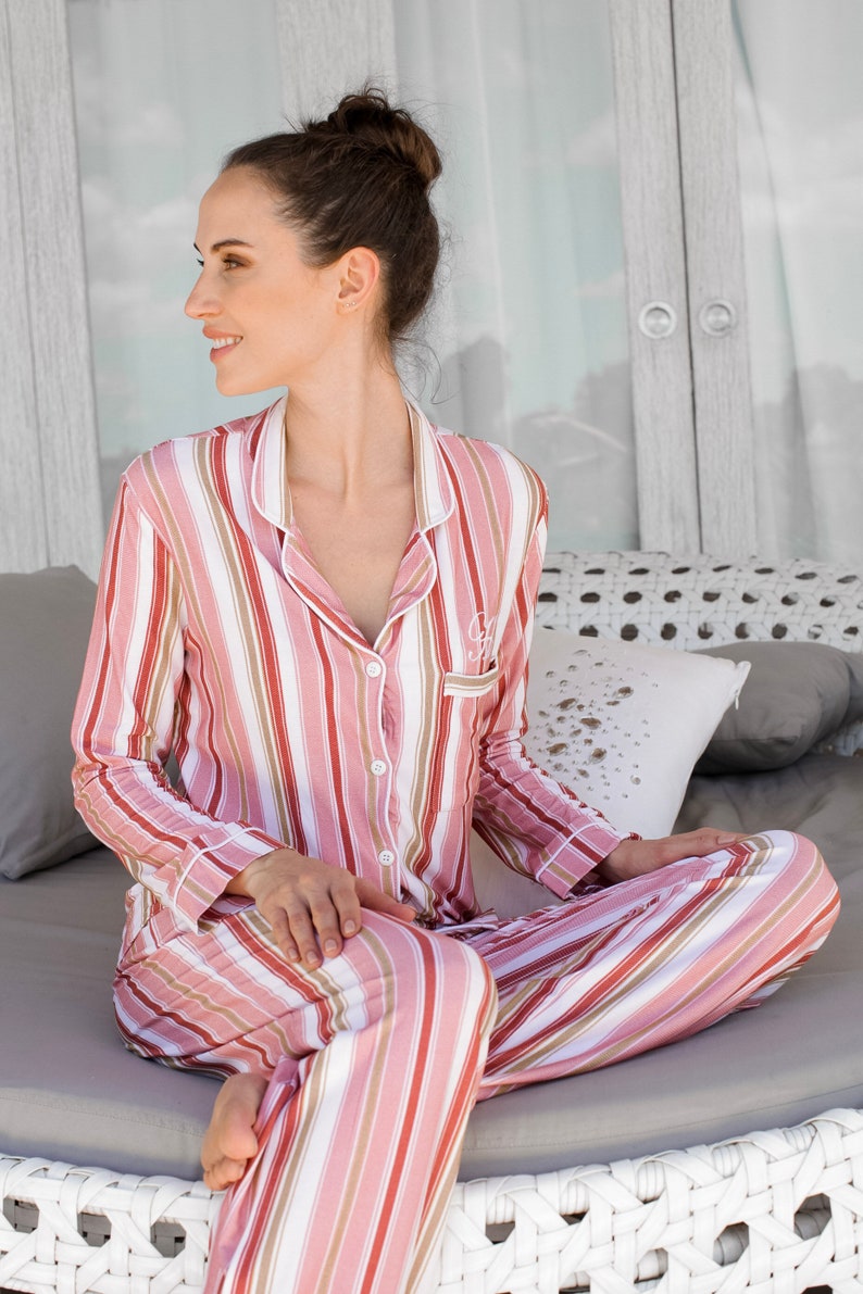 May include: A pink and white striped pajama set with long sleeves and pants. The pajamas have a button-up front and a relaxed fit.