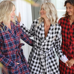 May include: Three women wearing plaid robes. The robes are in different colors and patterns. One robe is black and white, one is red and black, and one is blue and red.