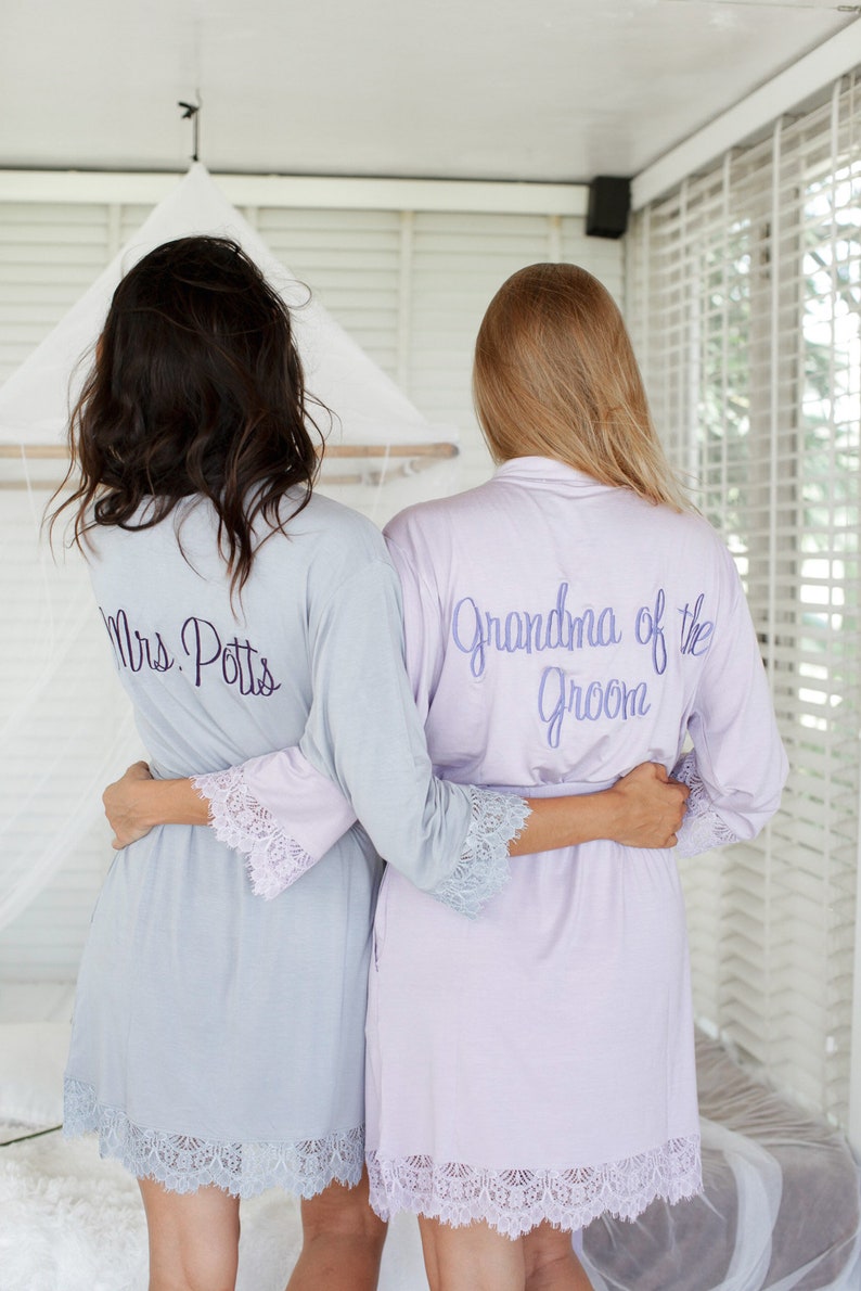 May include: Two women wearing matching light blue and lavender robes with lace trim. The robes are personalized with the text "Mrs. Potts" and "Grandma of the Groom".