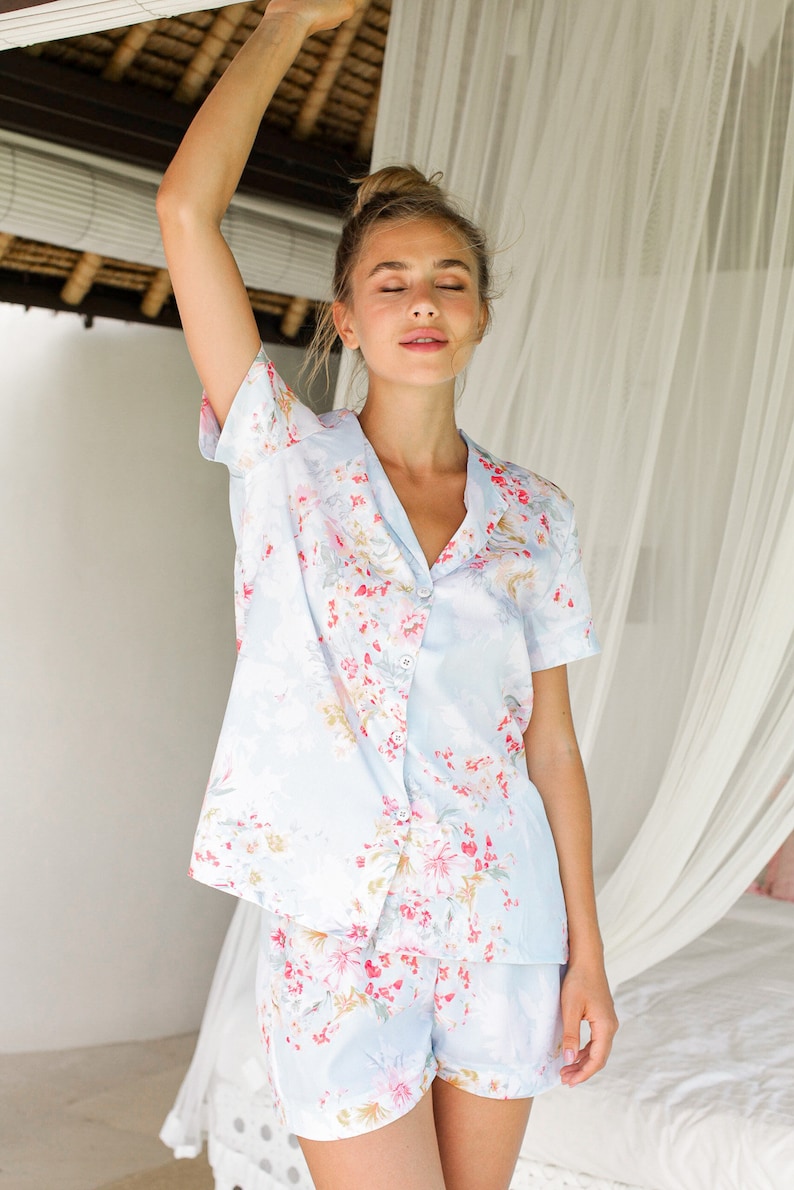 May include: A light blue pajama set with a floral print. The top has short sleeves and a button-up front. The shorts have a relaxed fit.