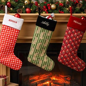 May include: Three personalized Christmas stockings hang above a fireplace. One is red with a white checkered pattern and the name "Jessica". Another is green with a pattern and the name "Ashley". The third is red with a floral pattern and the name "Michelle".