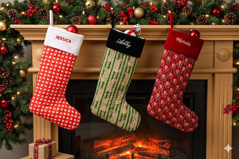 May include: Three personalized Christmas stockings hang above a fireplace. One is red with a white checkered pattern and the name "Jessica". Another is green with a pattern and the name "Ashley". The third is red with a floral pattern and the name "Michelle".