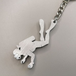 May include: Silver metal keychain featuring a scuba diver silhouette.