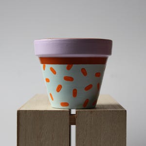 Op de afbeelding: Een witte keramische mok met een zwart handvat en de tekst "But First, Coffee" in een vetgedrukte, zwarte letter. De mok staat op een houten oppervlak. De mok is ongeveer 10 cm hoog.