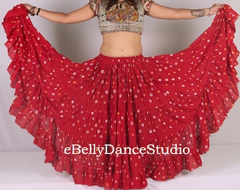 May include: A red, white, and yellow patterned circle skirt with multiple layers of ruffles. The skirt is made of a lightweight fabric and has a tie closure at the waist.