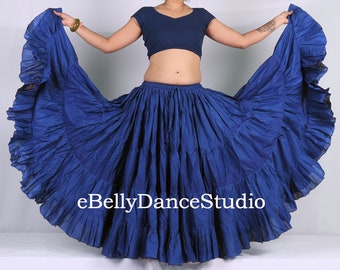May include: A solid dark blue tiered skirt with a wide, ruffled hemline and an elasticized waistband. The fabric features a gathered, voluminous design that flares outward. The text eBellyDanceStudio is printed in white across the center.
