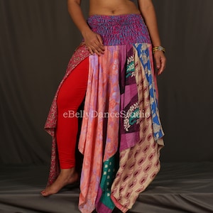 May include: A multi-colored patchwork skirt with a red, pink, blue, and green floral pattern. The skirt is made of several different fabrics and has a gathered waistband. eBellyDanceStudio is printed on the skirt.