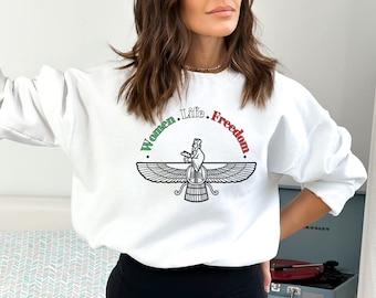 May include: White sweatshirt with a graphic print of a Faravahar symbol, a winged figure with a crown, and the text "Women. Life. Freedom." in green, red, and white.