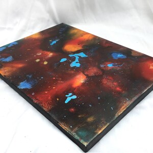 Pu&ograve; includere: Dipinto astratto su tela con sfondo scuro e schizzi di vernice arancione, rossa e blu.