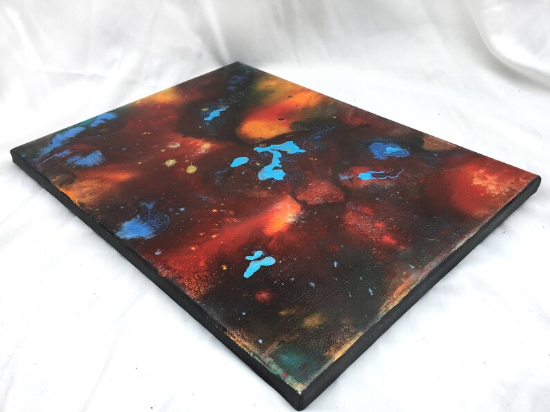 Pu&ograve; includere: Dipinto astratto su tela con sfondo scuro e schizzi di vernice arancione, rossa e blu.