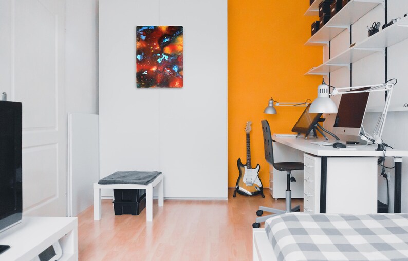 Pu&ograve; includere: Una scrivania bianca con una sedia bianca e un monitor per computer. C'&egrave; una chitarra appoggiata alla scrivania e un dipinto sul muro dietro la scrivania.