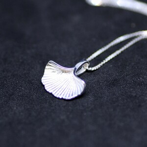 May include: A silver necklace featuring a ginkgo leaf pendant. The pendant is detailed with fine lines and has a delicate, feminine design.