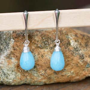 May include: A pair of silver dangle earrings with light blue teardrop-shaped stones.