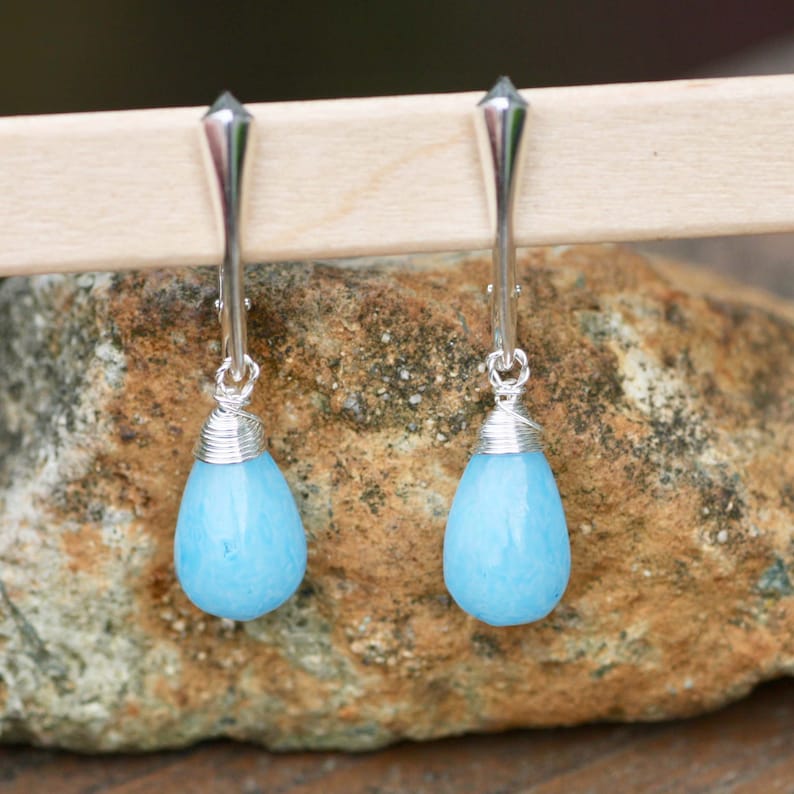May include: A pair of silver dangle earrings with light blue teardrop-shaped stones.