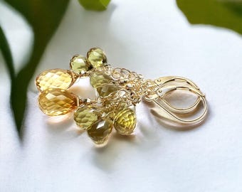 May include: Gold-colored earrings with multiple faceted, yellow-green gemstones. The earrings have a lever-back closure and are set on delicate gold chains. The gemstones vary in size and shape, creating a layered effect.