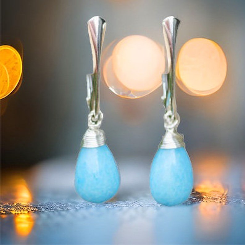 May include: A pair of silver dangle earrings with light blue teardrop-shaped stones.