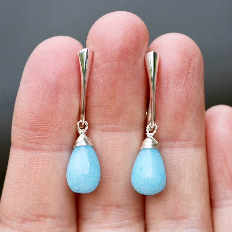 May include: A pair of silver dangle earrings with light blue teardrop-shaped stones.