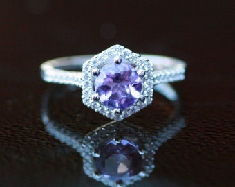 May include: A silver ring with a large, round, purple amethyst gemstone surrounded by a halo of smaller, clear gemstones.