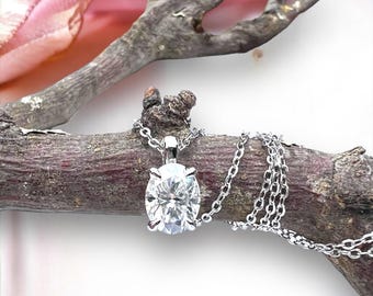 May include: A silver chain necklace with a large, clear oval-shaped pendant.