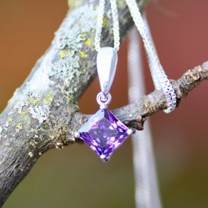 May include: A silver necklace with a square-shaped pendant featuring a purple gemstone.
