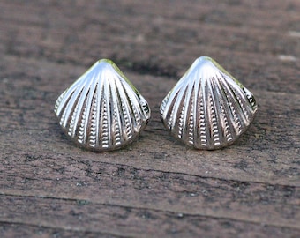 Può includere: Un paio di orecchini a forma di conchiglia d'argento. Gli orecchini sono piccoli e delicati, e hanno un design dettagliato.