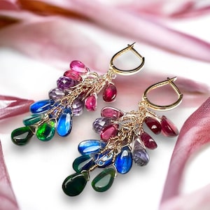 May include: Gold-coloured earrings featuring clusters of colourful gemstones in shades of green, blue, purple, pink, and red. The earrings have a delicate, dangling design with a gold hoop closure. The gemstones are measured in centimetres.