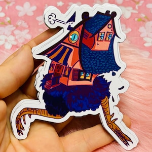 Könnte beinhalten: Ein bunter Aufkleber mit einem Cartoon-Haus mit blauem Dach und einem rot-gelb gestreiften Vordach, das auf dem Rücken eines schwarz-blauen Vogels mit orangefarbenen Beinen sitzt.