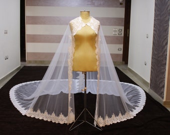 May include: A white bridal veil with a lace trim. The veil is draped over a dress form and has a long train.