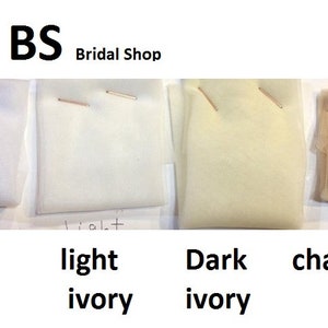 Puede incluir: Cuatro muestras de tejido de tul en diferentes colores: blanco, marfil claro, marfil oscuro y champ&aacute;n. Las muestras est&aacute;n etiquetadas con los nombres de colores correspondientes.