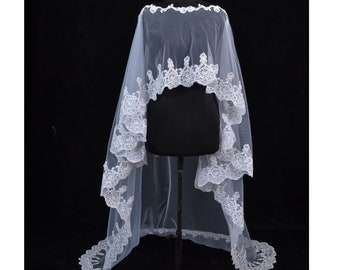 May include: White bridal veil with a lace trim. The veil is long and flowing, with a scalloped edge.