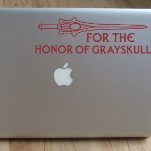 May include: A red sticker on a silver laptop with a sword and the text "FOR THE HONOR OF GRAYSKULL".