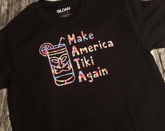 Camiseta unisex "Make America Tiki Again" (inspirada en la cultura Tiki retro y las tazas Tiki). Cuello redondo. Múltiples opciones de talla y color.