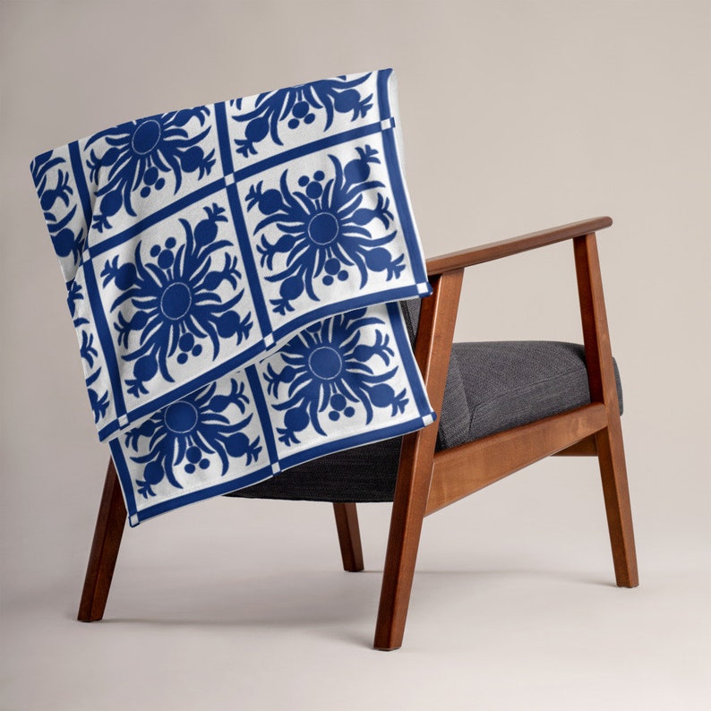 Puede incluir: Una manta de tiro azul y blanca con un patr&oacute;n geom&eacute;trico y floral, colocada sobre un sill&oacute;n de madera.