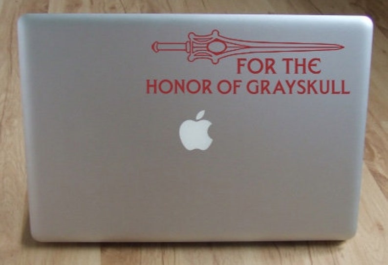 May include: A red sticker on a silver laptop with a sword and the text "FOR THE HONOR OF GRAYSKULL".