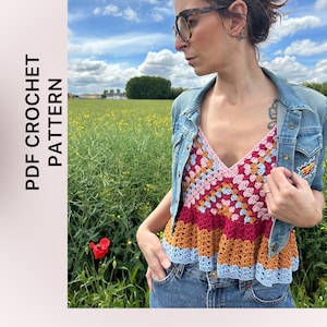 Peut inclure: Un haut en crochet avec un motif de granny squares multicolores. Le haut a un col en V et un ourlet à volants. Le haut est porté sur un jean bleu.