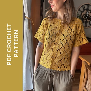 Può includere: Top all'uncinetto giallo senape con maniche corte e bottoni in legno. Il top presenta un orlo smerlato e un delicato motivo traforato. Il testo "PDF CROCHET PATTERN" è stampato verticalmente sul lato sinistro dell'immagine.