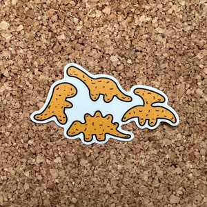 May include: Four yellowish tan dinosaur  nugget stickers on a corkboard background. The dinosaurs are in various poses. The stickers are made of a vinyl material
