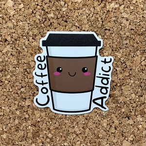 Könnte beinhalten: Eine weiße Kaffeetasse mit braunem Deckel und brauner Hülle. Die Tasse hat ein Comic-Gesicht mit rosa Wangen und einem Lächeln. Der Text "Coffee Addict" steht auf beiden Seiten der Tasse.