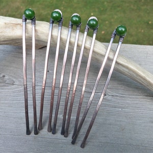 May include: Five U-shaped hair forks crafted from hammered copper wire. Each fork features two prongs and a single dark green spherical bead secured at the top with intricate wire wrapping. The metal has a warm, reddish-brown metallic finish.