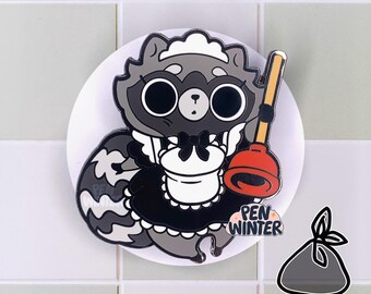 May include: A black and white enamel pin of a raccoon wearing a maid outfit and holding a plunger. The raccoon has a black bow and a white apron. The pin says "Pen Winter" on the bottom.